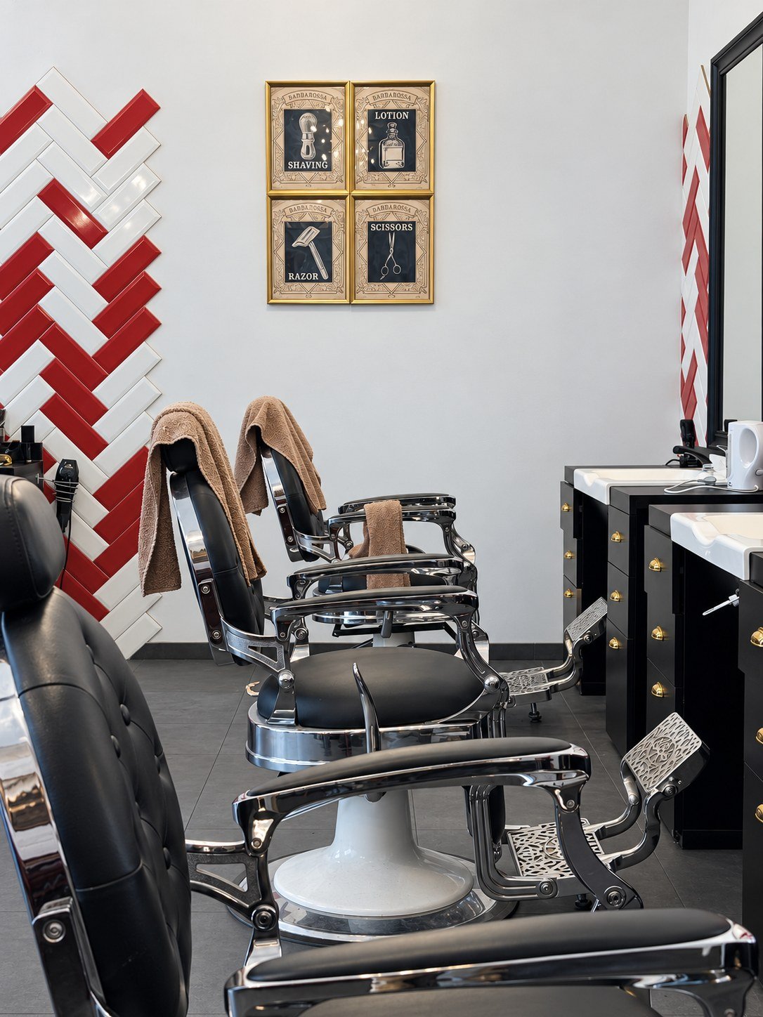 Reihe schwarzer Barbierstühle mit Chromdetails und Fußrasten, an der Wand vier gerahmte Barber-Motive